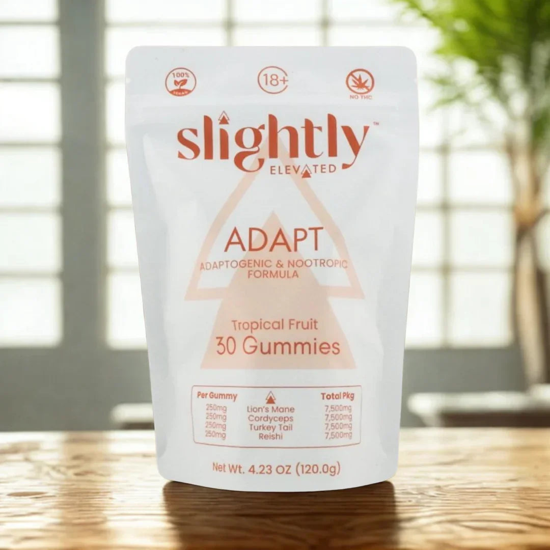 Slightly Elevated Adapt Gummies 30ct by Slightly Elevated sits on a wooden surface with greenery blurred in the background, highlighting adaptogens and nootropics for stress relief.